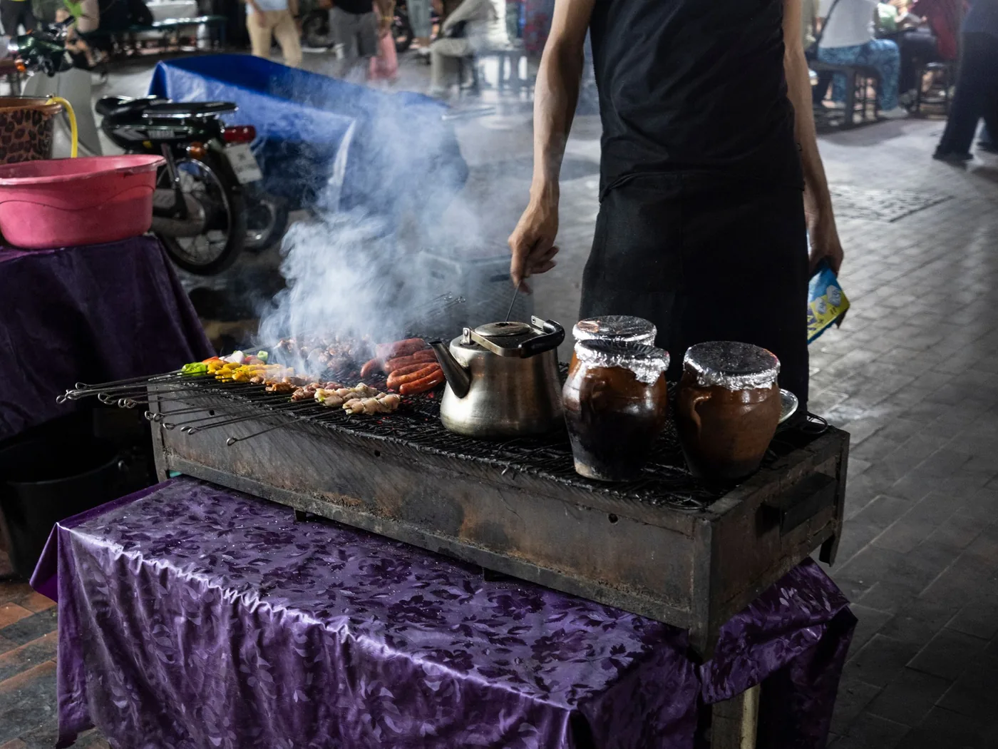 Grilled meat and skewers cooking over hot coals at a street stall