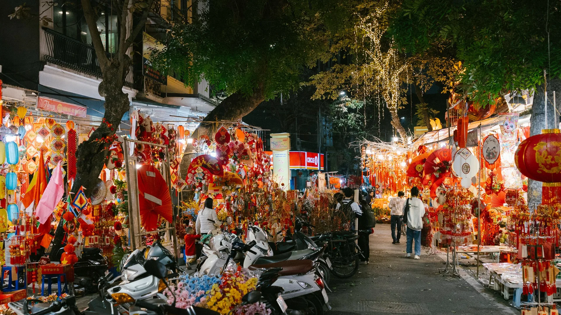 A busy Hanoi Old Quarter street at night with food stalls and low plastic stools
